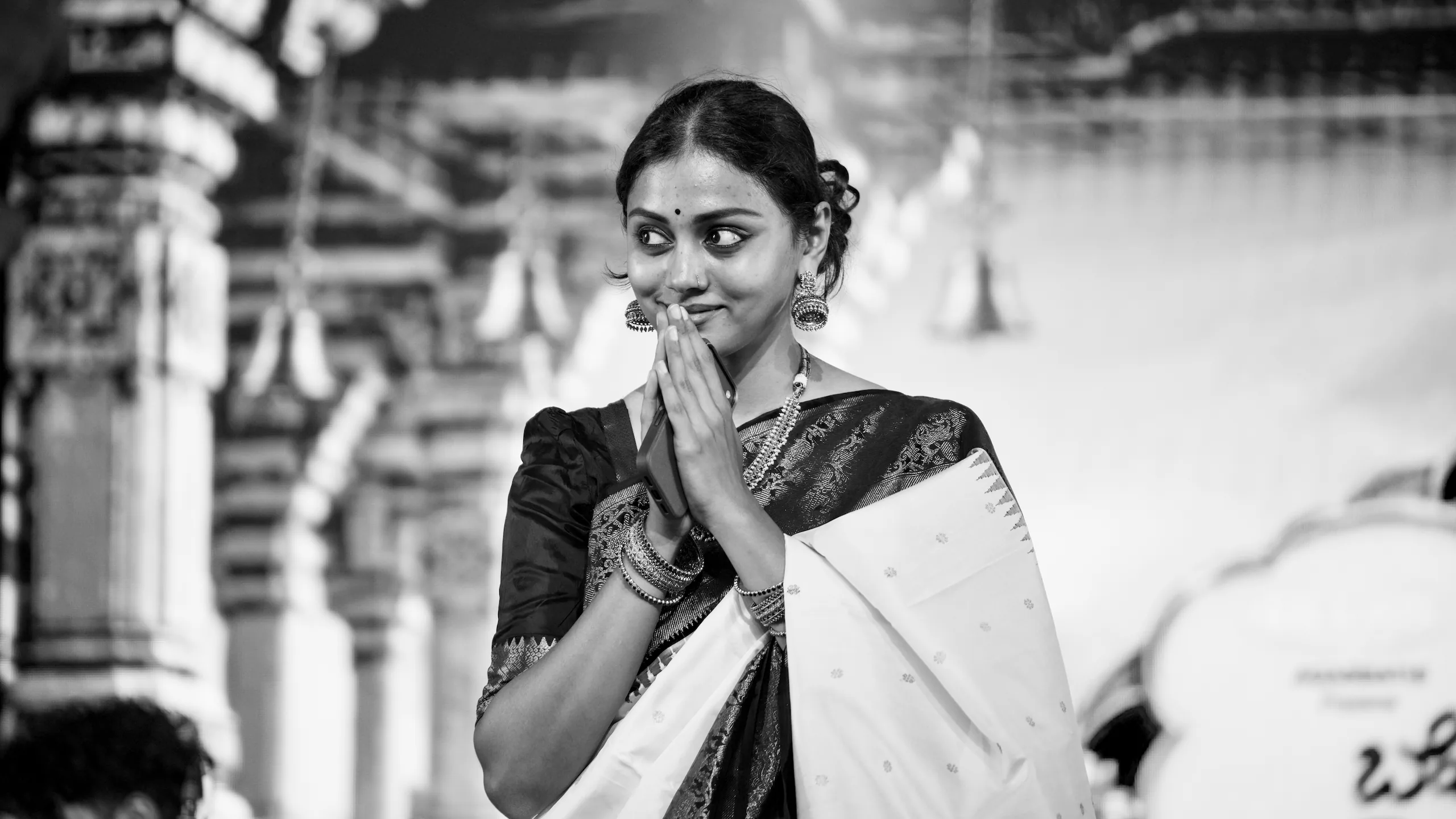 Sivasri Tejasvi Surya in a saree with her palms joined in a namaste, smiling and looking to one side