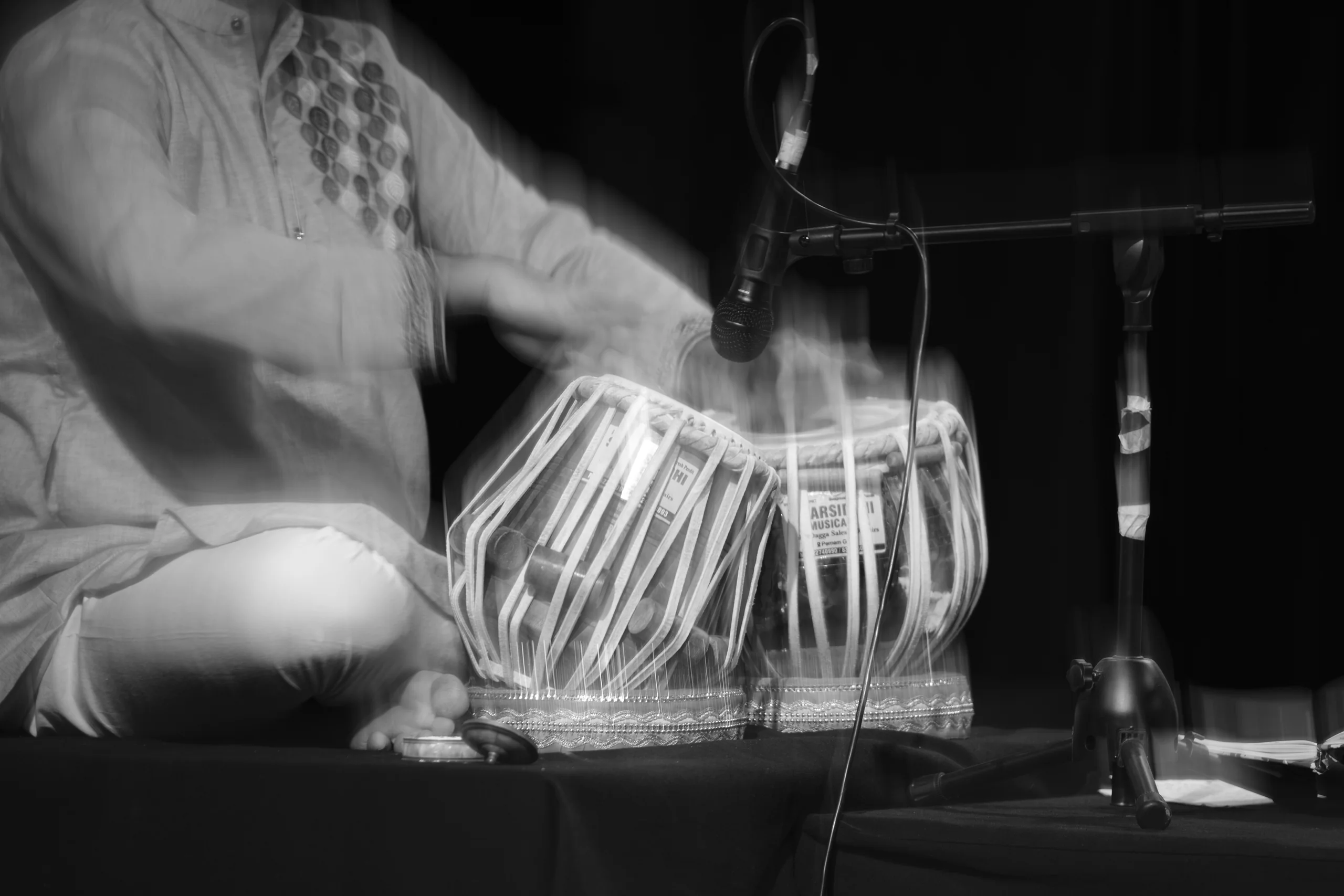 A long exposure of a tabla solo, where the tihai resolves somewhere between the drums holding still and the hands smearing into the rhythm they are making.