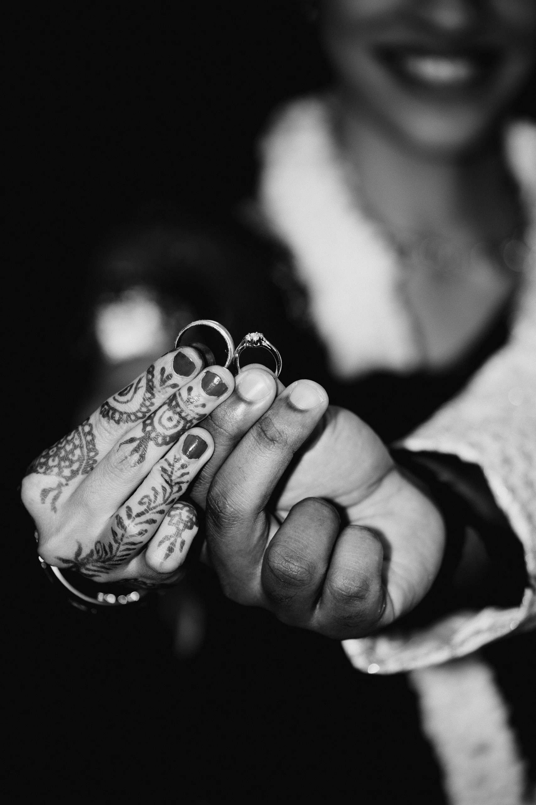 The smile that made the rest of it a formality is the whole point of this frame, even out of focus behind two rings held up to the lens, with hands clasped around them.
