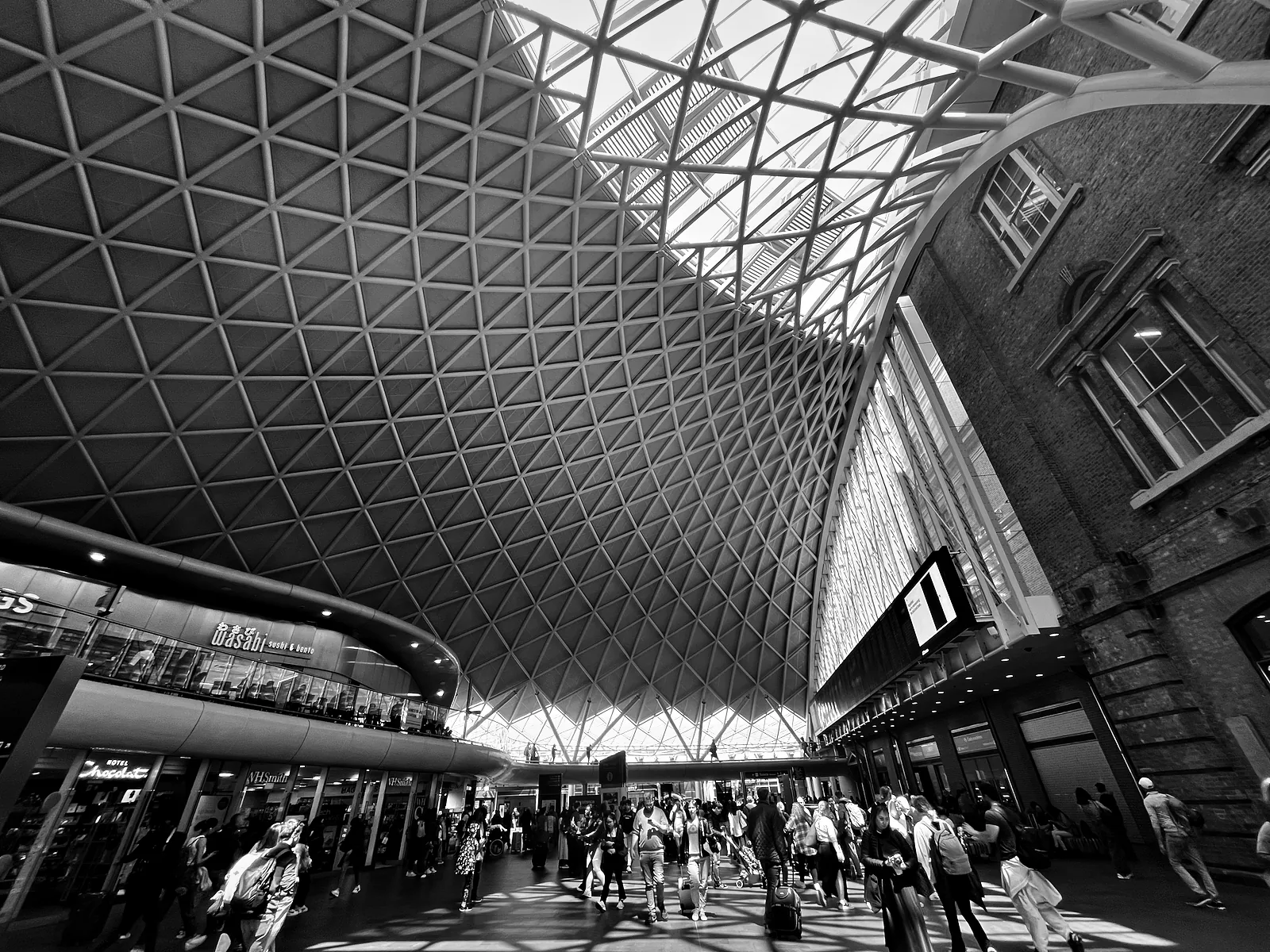 The lattice roof of the western concourse at King's Cross above the crowd