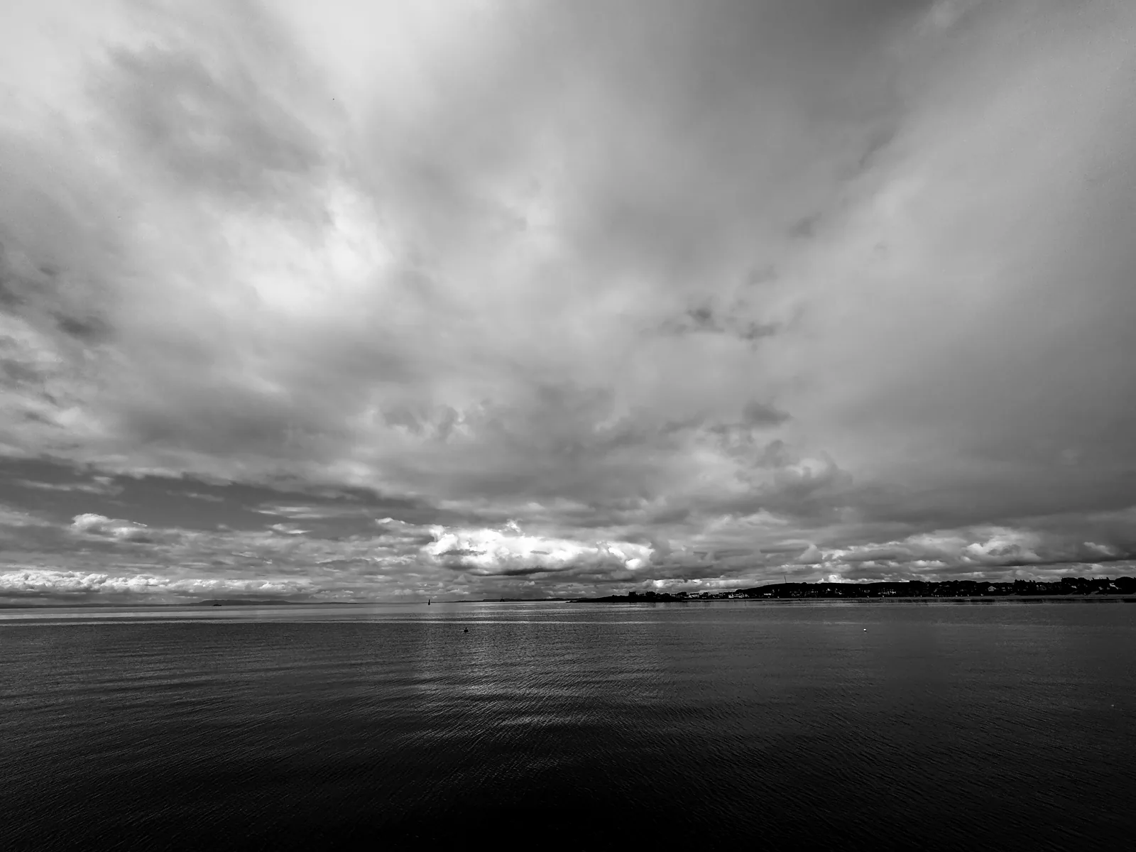The Firth of Forth flat calm under a wide grey sky at Elie