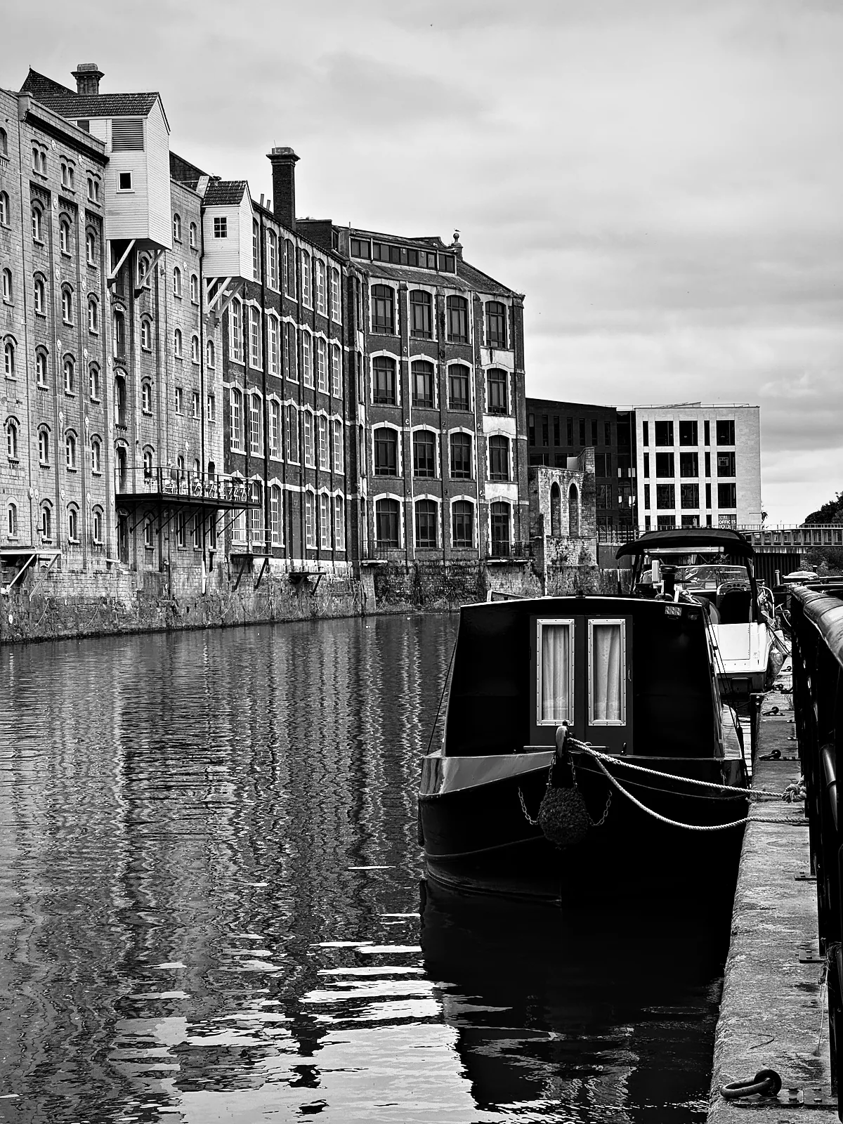 A narrowboat moored on the Avon below old mill buildings in Bath