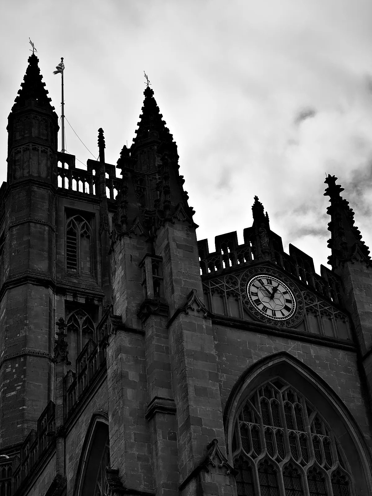 The pinnacles and clock of Bath Abbey against a grey sky